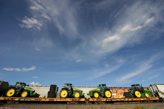 A fleet of trucks loaded with fresh agricultural produce ready for transport under a clear blue sky.