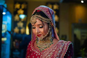 Close-up of a woman smiling softly, wearing delicate rose gold dangler earrings with a bridal outfit.