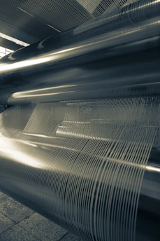 Close-up of shiny stainless steel coils stacked in a modern industrial warehouse.