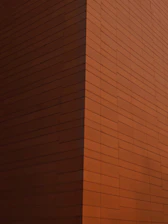 Modern residential building with minimalist architecture in Asturias, showcasing clean lines and warm rust tones.