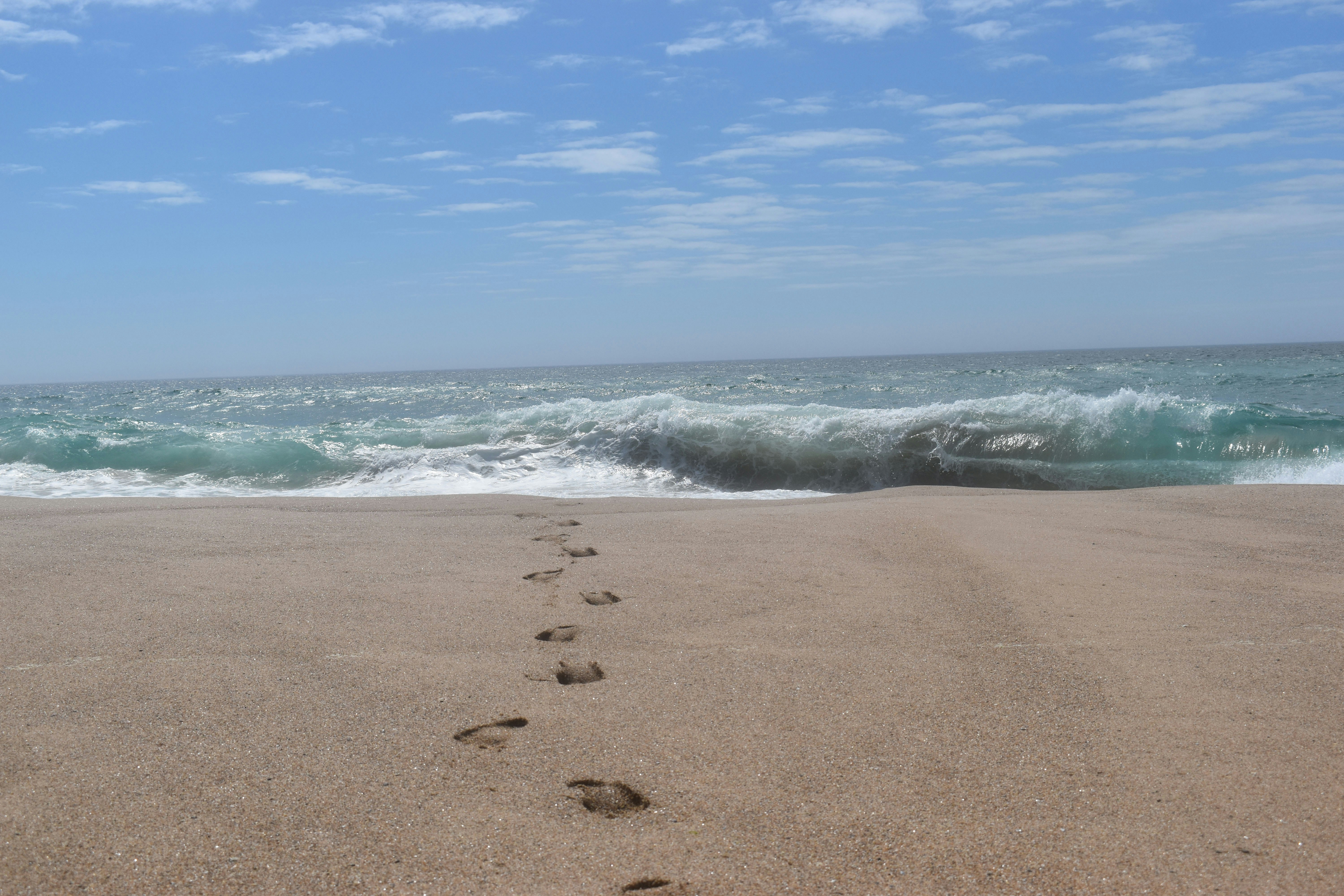 a person's foot prints in the sand near the ocean