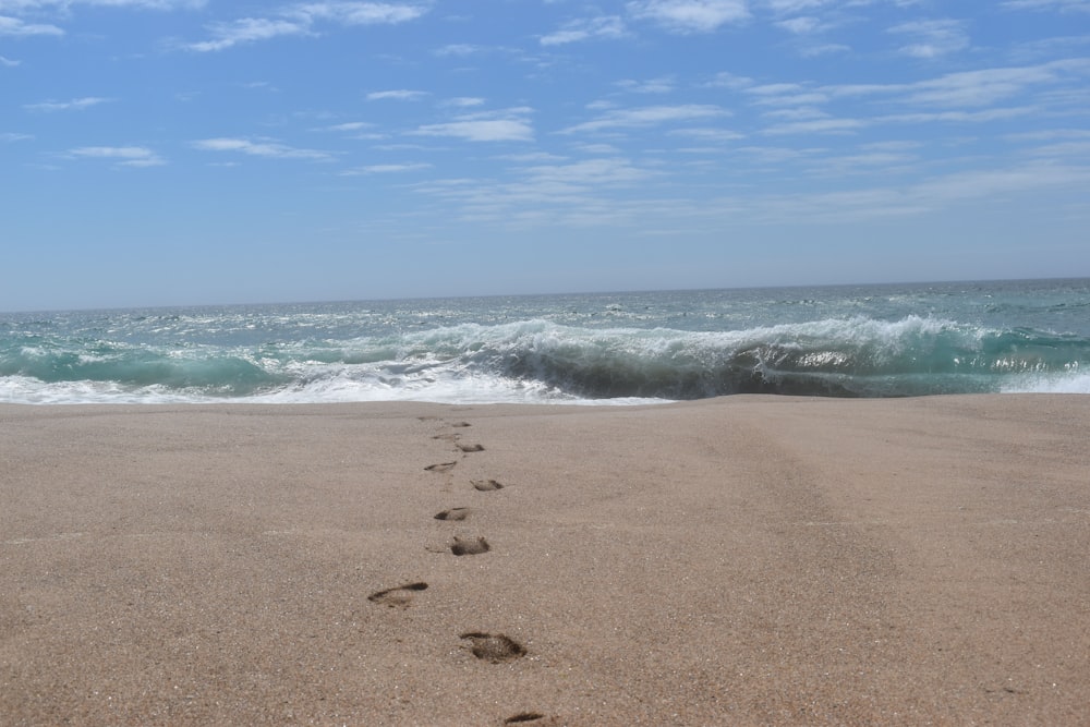 a person's foot prints in the sand near the ocean