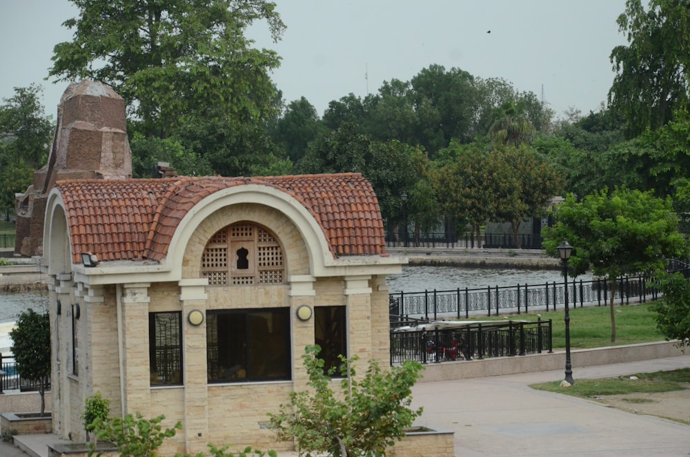 a building with a red tiled roof next to a body of water