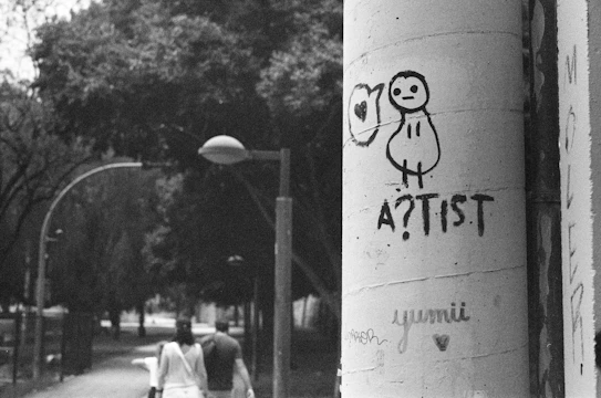 A candid photo of a South African street artist at work, surrounded by vibrant urban murals under moody lighting.
