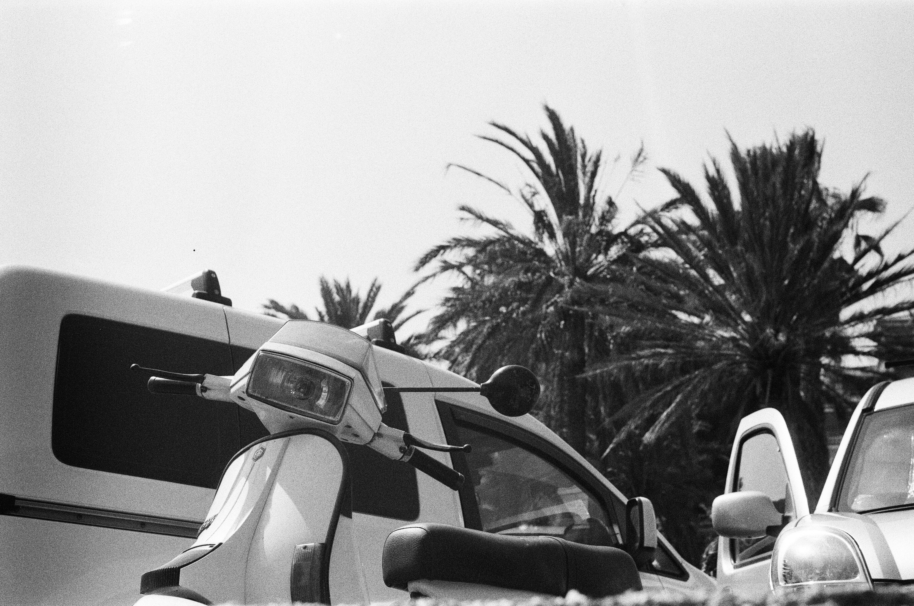 a motor scooter parked next to a parked car
