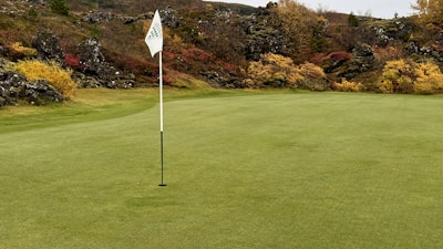 Crowd cheering by the final hole with colorful fall foliage in the background.
