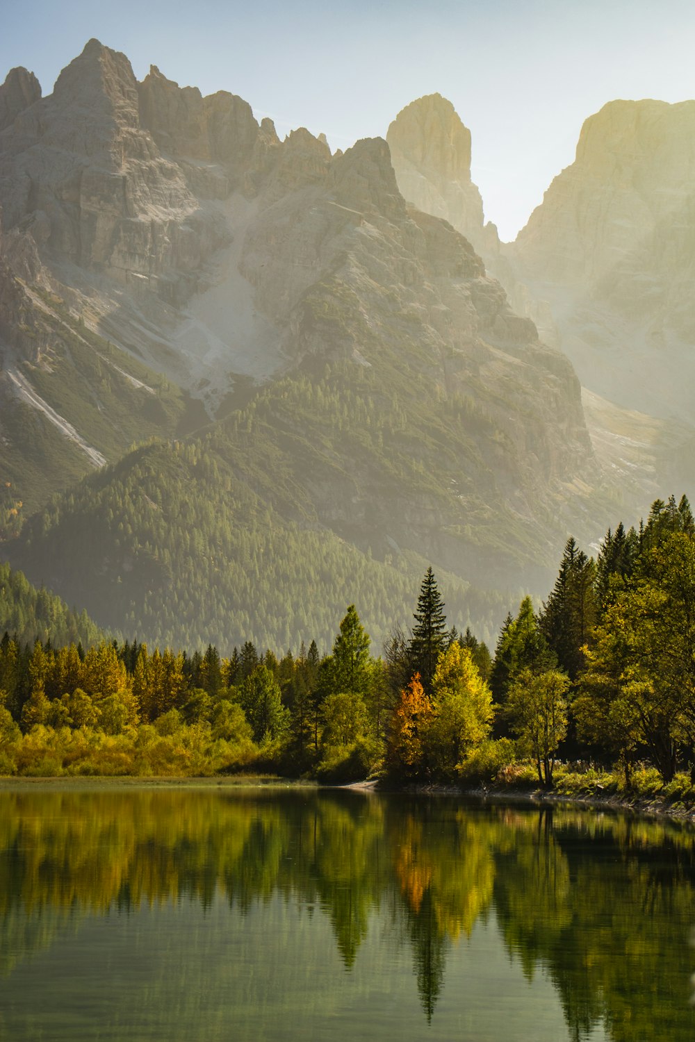 a lake surrounded by mountains with trees in the foreground