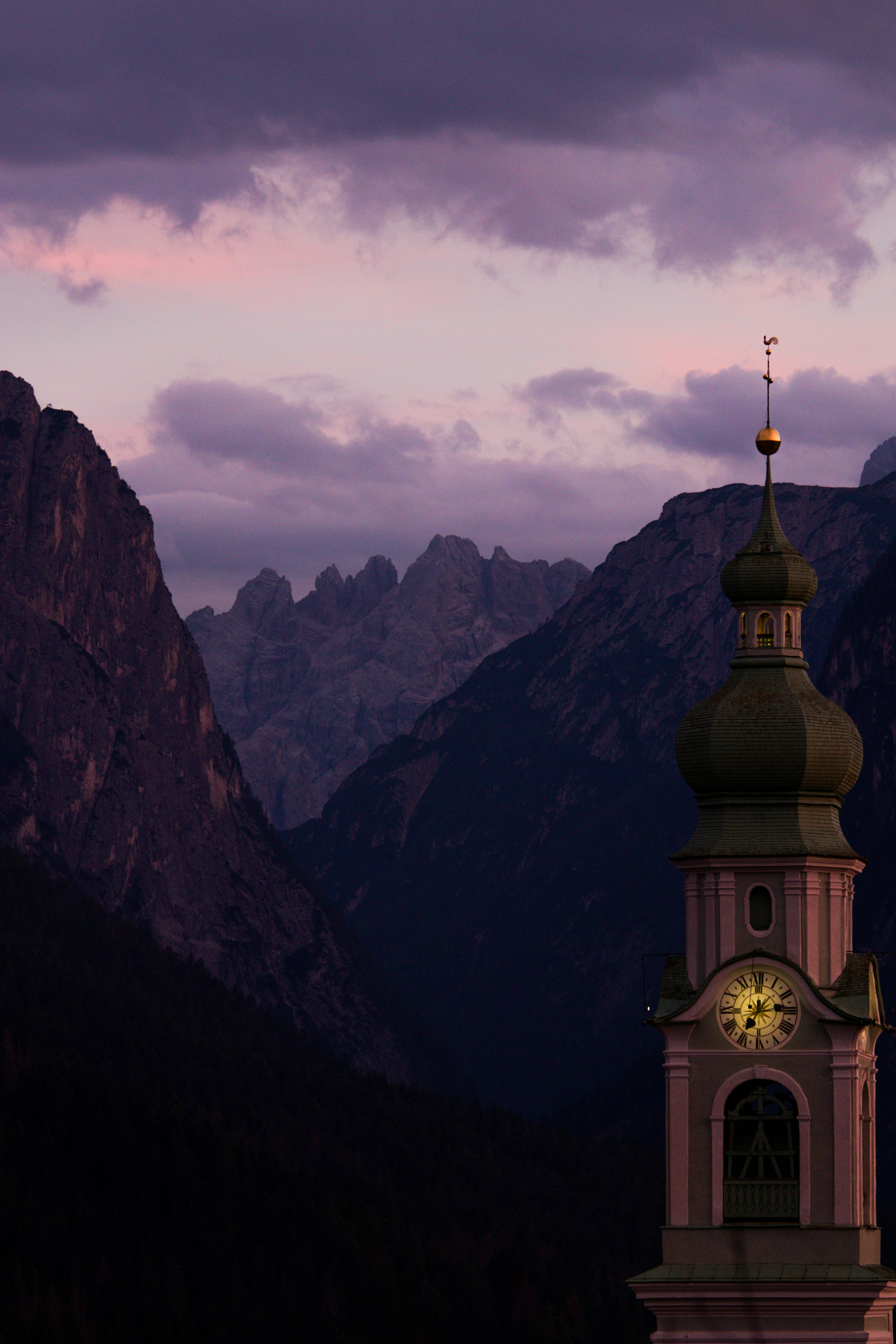 a clock tower in the middle of a mountain range
