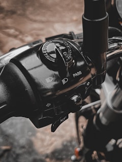 A detailed view of a motorcycle control panel, featuring switches and controls for headlights and pass signals. The branding of a motorcycle company is visible on the rotary switch. The metallic and plastic components are highlighted with reflections and shadows.