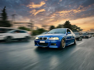 Electric blue-accented sports car speeding along a coastal highway at sunset.