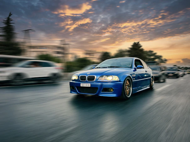 Electric blue-accented sports car speeding along a coastal highway at sunset.