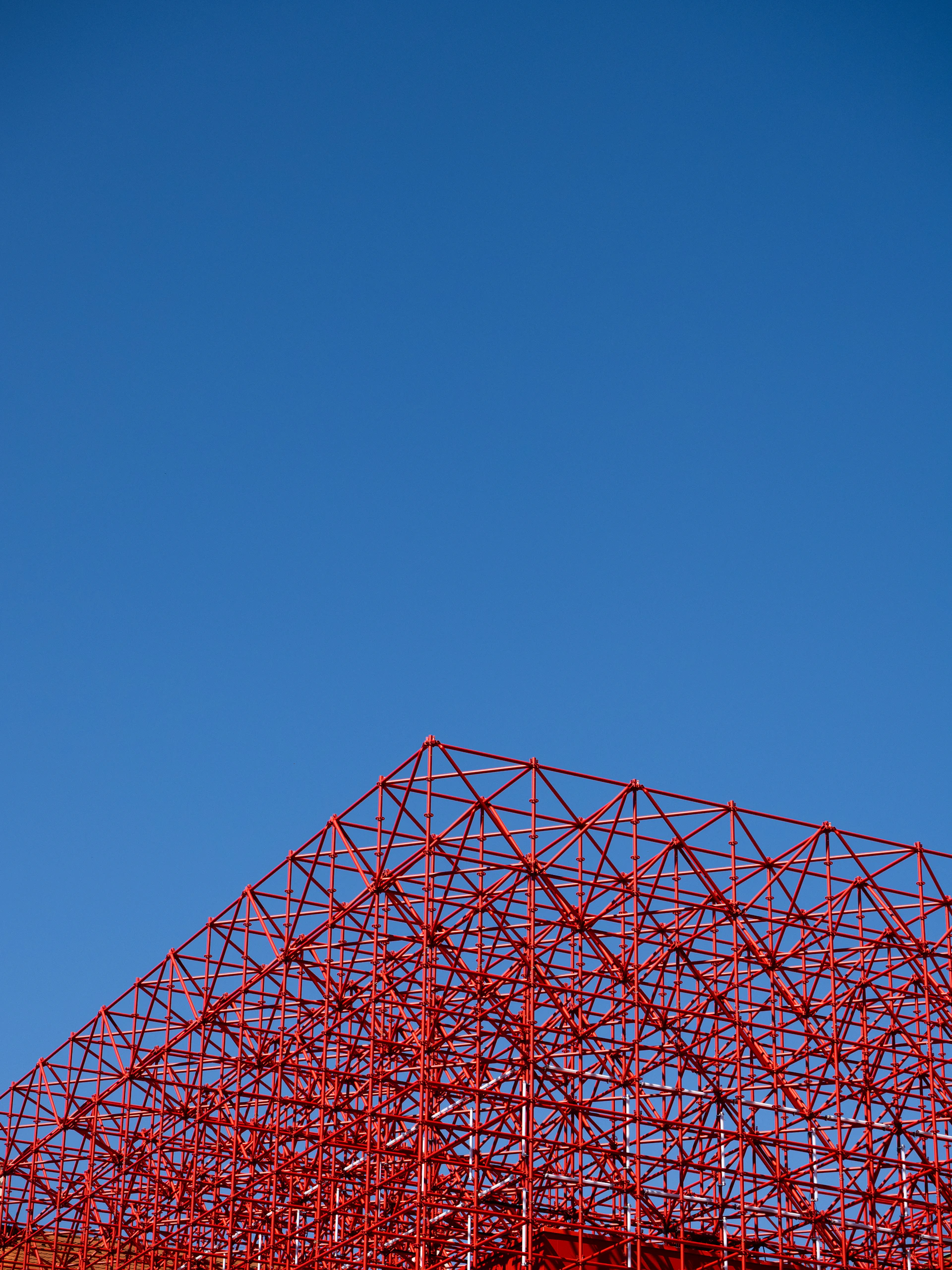 an airplane flying over a red structure under a blue sky