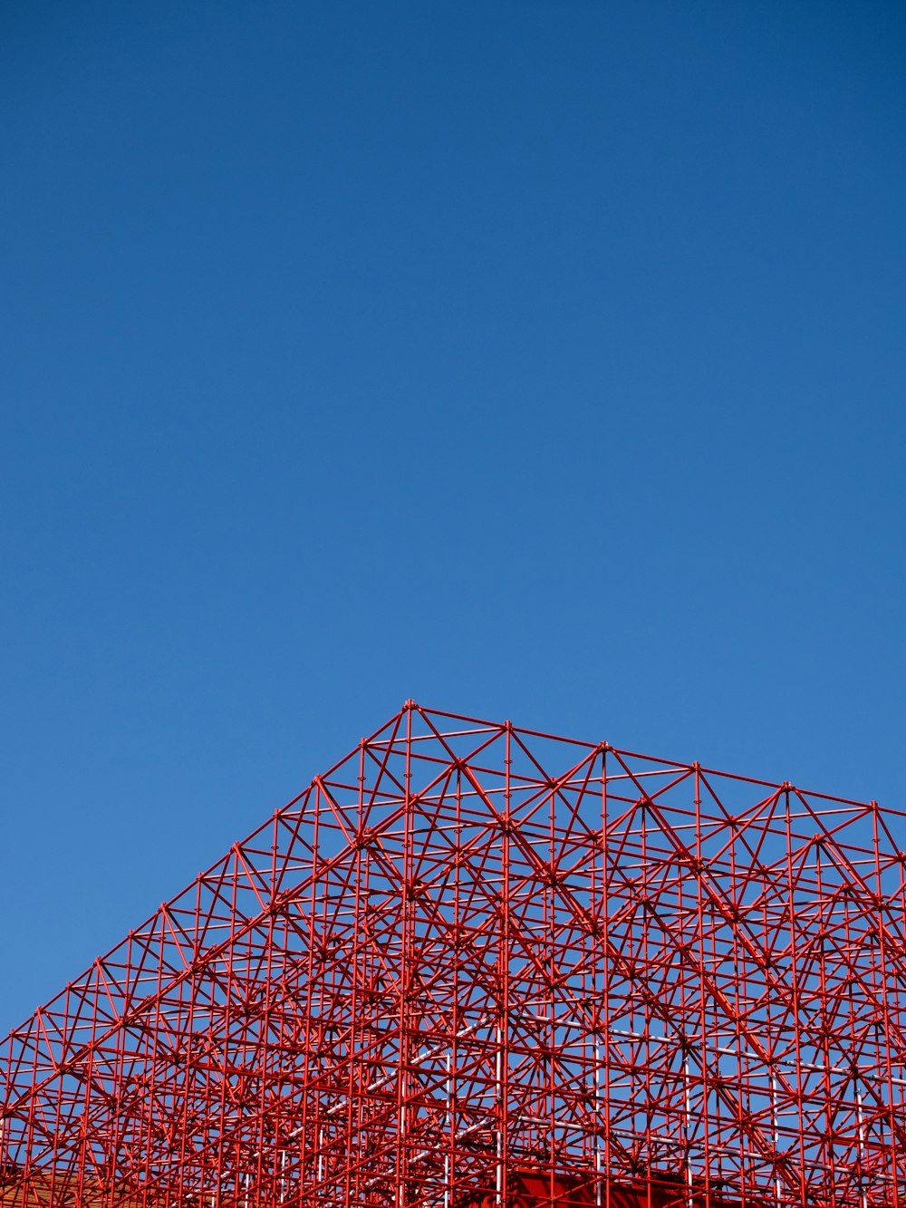 an airplane flying over a red structure under a blue sky