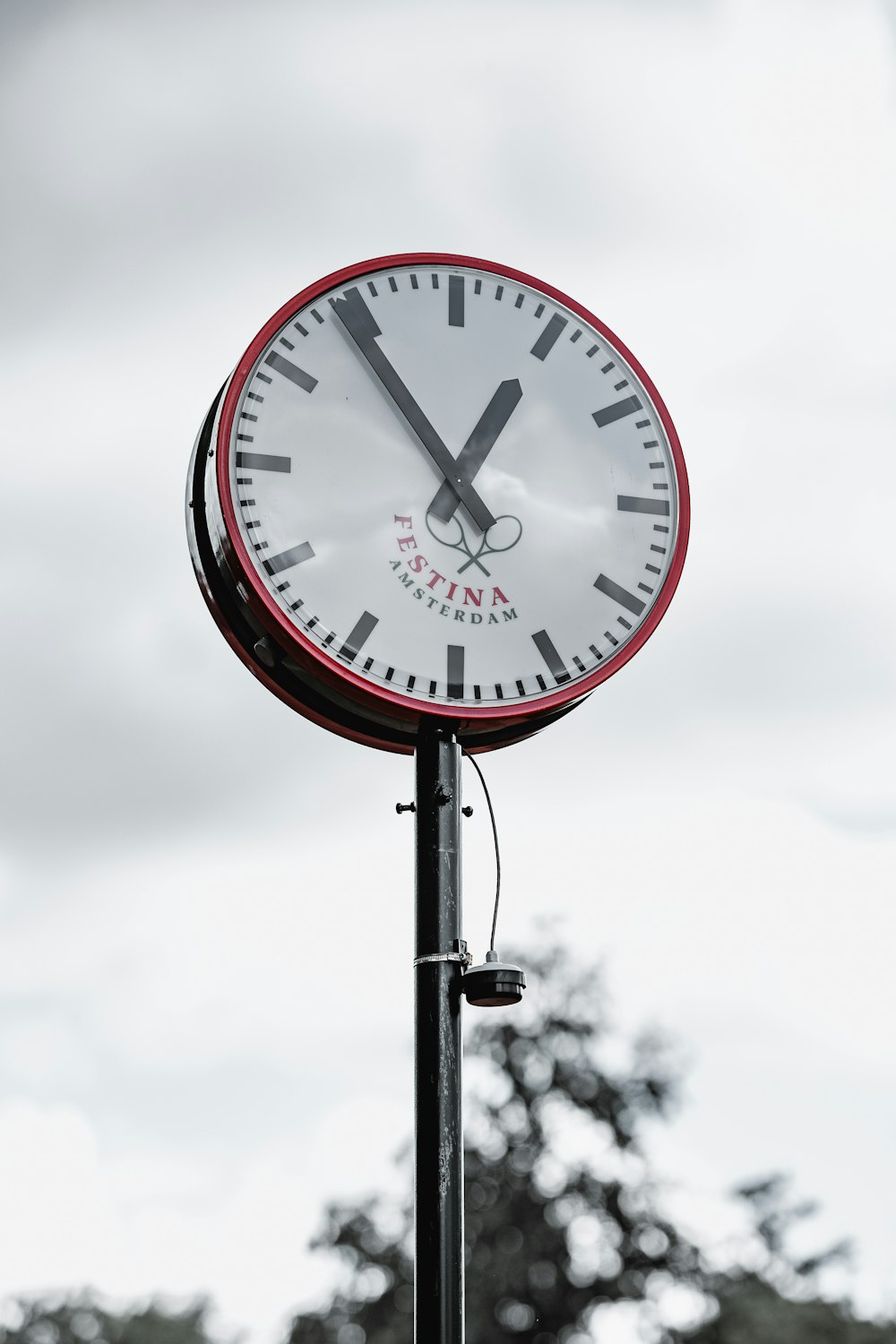 a clock on a pole with trees in the background