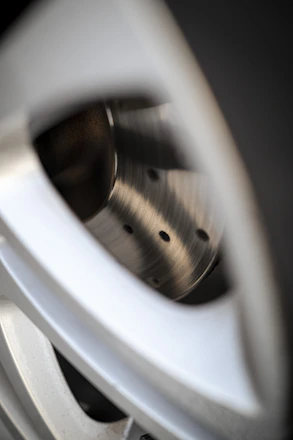 Close-up of a sleek aluminium forged wheel gleaming under soft lighting.