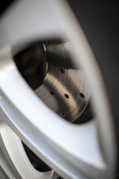 Close-up of a sleek, ultra-precision car wheel shining under soft light, highlighting its intricate design and craftsmanship.