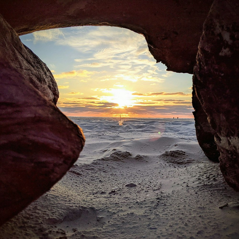 a view of a beach through a hole in a rock