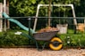 a wheelbarrow filled with dirt next to a playground