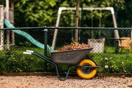 a wheelbarrow filled with dirt next to a playground