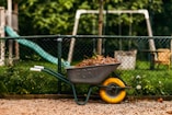 a wheelbarrow filled with dirt next to a playground