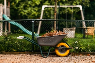 a wheelbarrow filled with dirt next to a playground