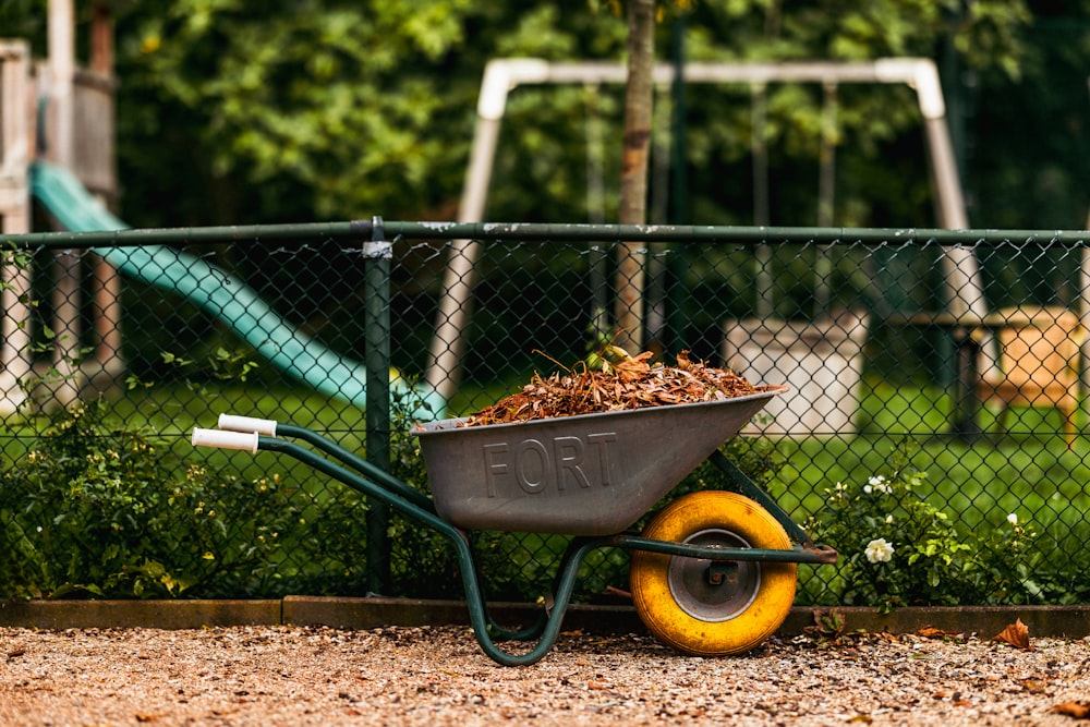 a wheelbarrow filled with dirt next to a playground