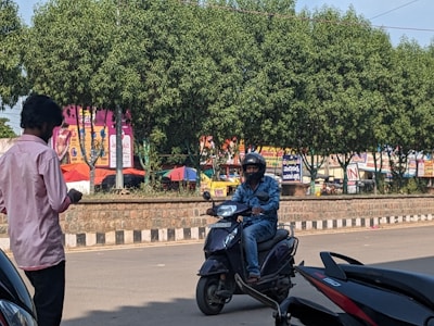 A person riding a scooter down a sunny road.