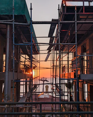 scaffolding surrounding a building with the sun setting in the background