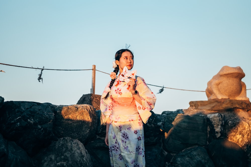 a woman in a kimono standing in front of some rocks