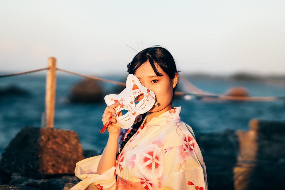 Eine Frau in einem Kimono hält eine Maske in der Hand