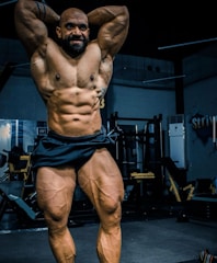 A bodybuilder practicing posing techniques in front of a laptop during an online class.
