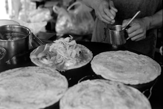 Close-up of a chef expertly spreading batter on a hot crepe griddle in a bright kitchen.