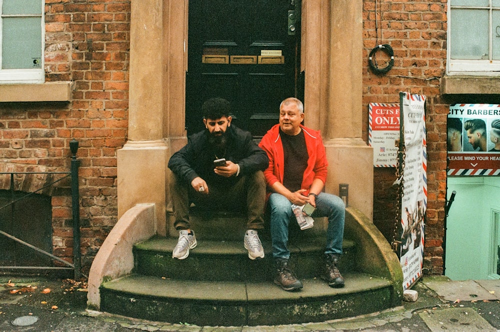 two men sitting on the steps of a building