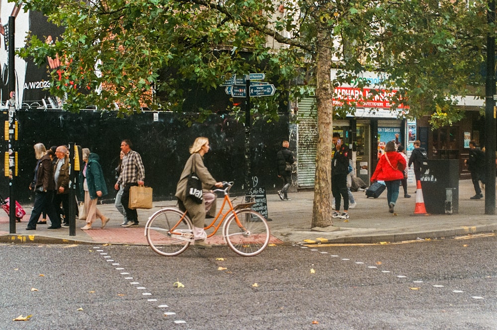 a man riding a bike down a street next to a tree