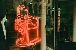 Modern blue LED acrylic sign illuminating a stylish barber shop interior at night.