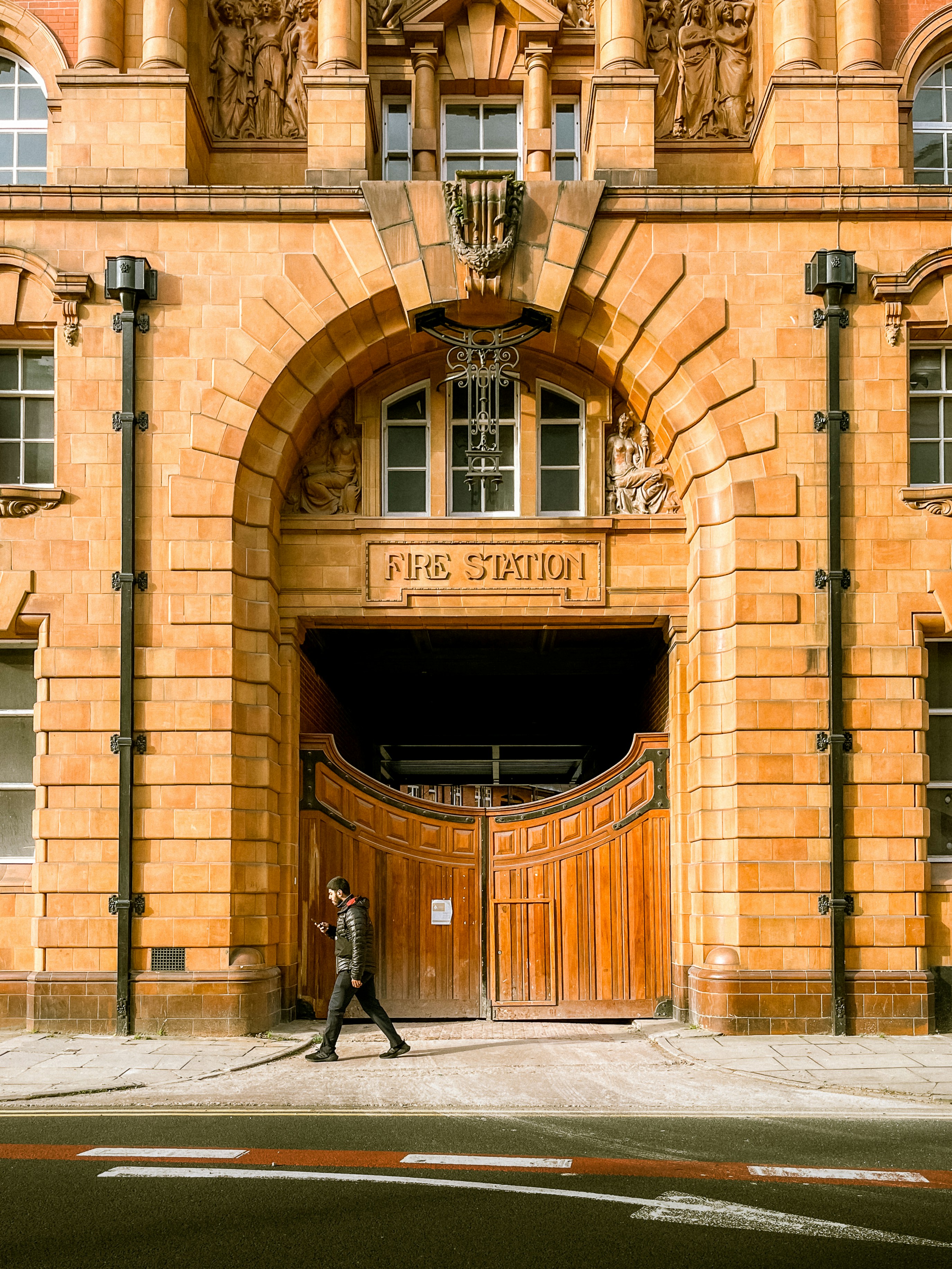 A man walking in front of a large building photo – Free Street Image on ...