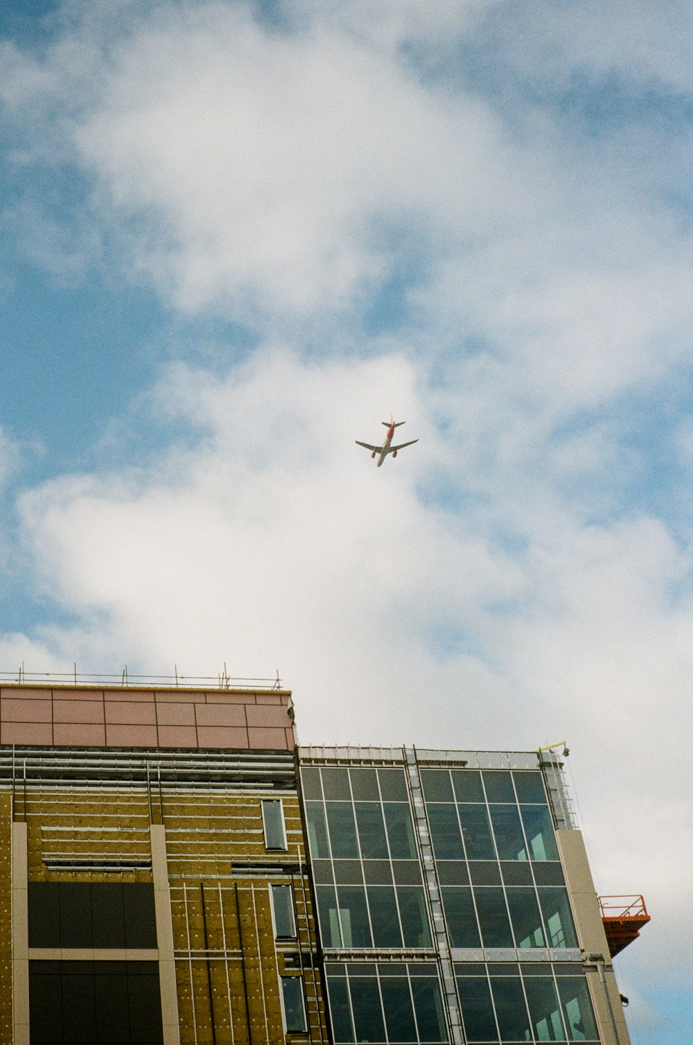 an airplane flying over a building under a cloudy sky
