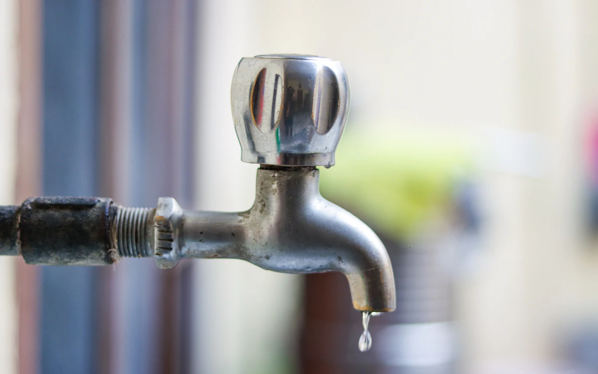 Close-up of a faucet with a single water drop falling