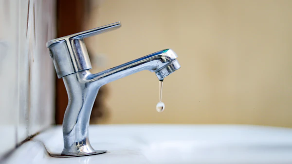 Faucet with a water droplet forming — classic leak symptom