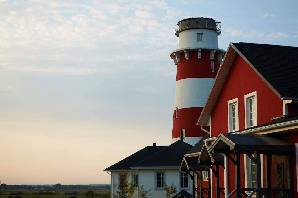 a red and white house with a light house in the background