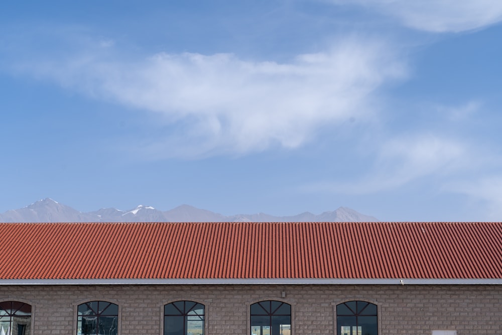 a building with a red tiled roof and mountains in the background
