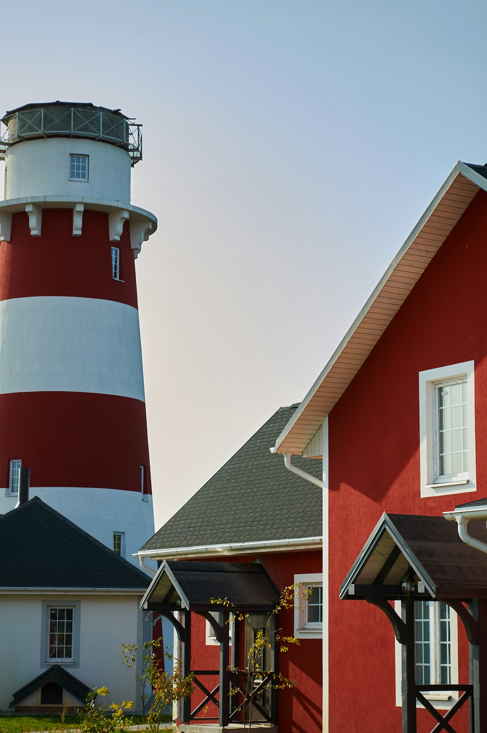a red and white lighthouse next to a red house