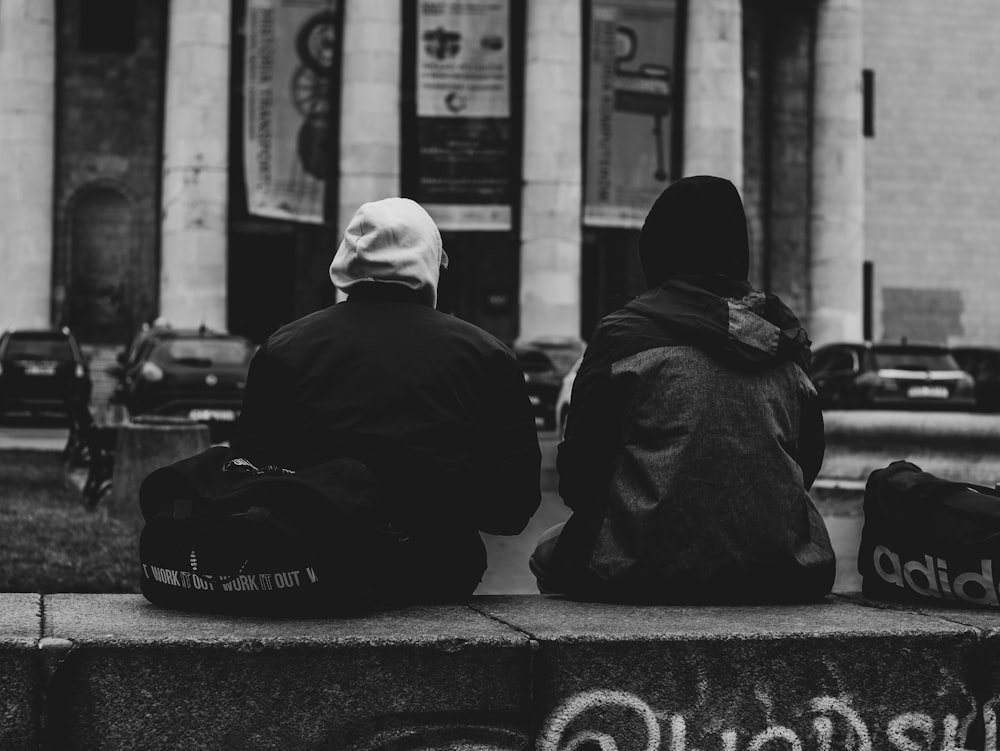 a couple of people sitting on top of a cement bench