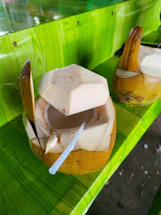 A close-up of fresh coconuts and a rustic wooden table with a handwritten note.
