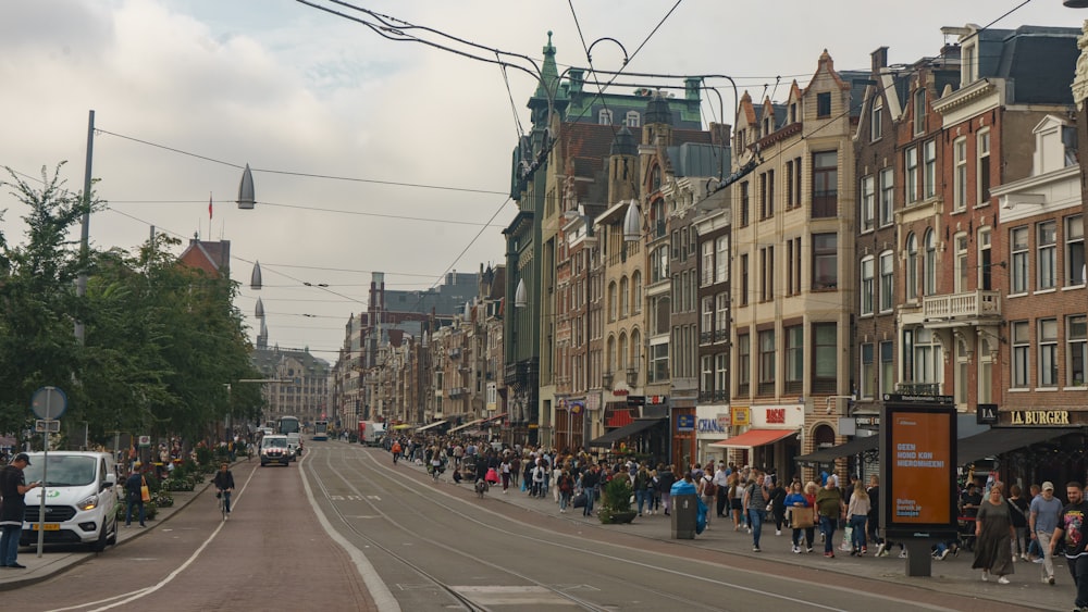 a group of people walking down a street next to tall buildings