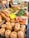 A bustling market stall displays a variety of fresh vegetables, prominently featuring squash and pumpkins. Other produce includes carrots, leafy greens, and zucchini. A vendor stands behind the counter, assisting customers.