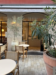 a patio with tables and chairs and a potted plant