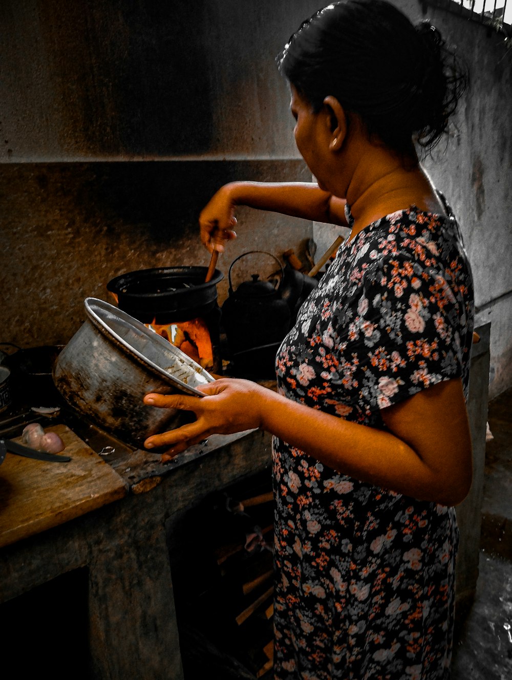 a woman cooking food in a pot on a stove