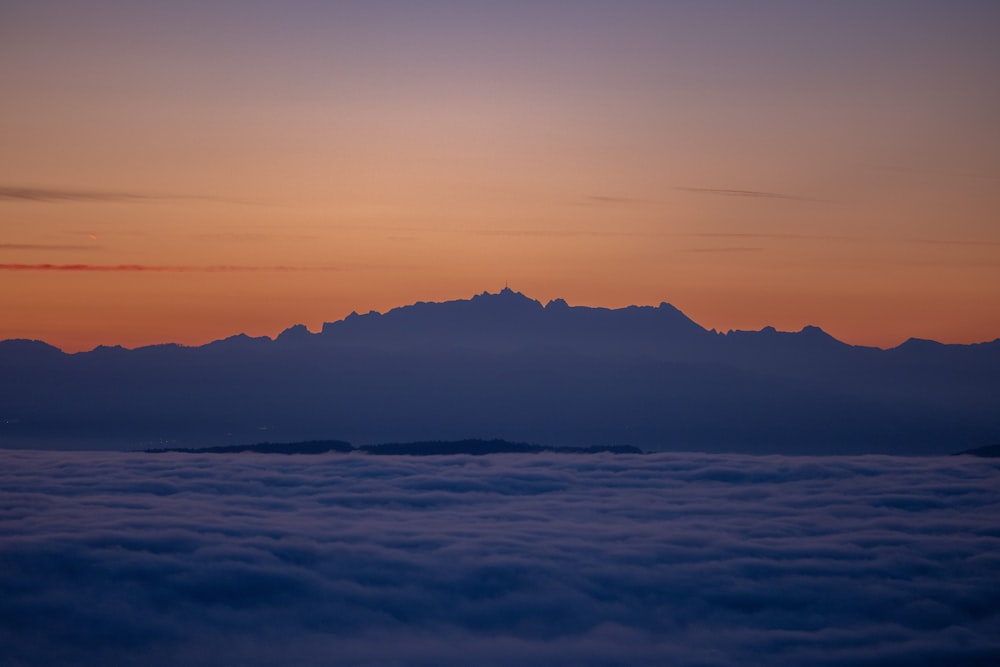 Le soleil se couche sur les montagnes au-dessus des nuages