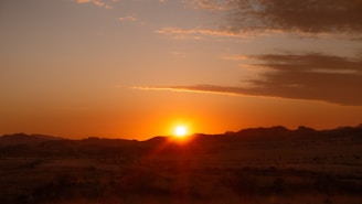 Sunset view over open land plots with distant hills.